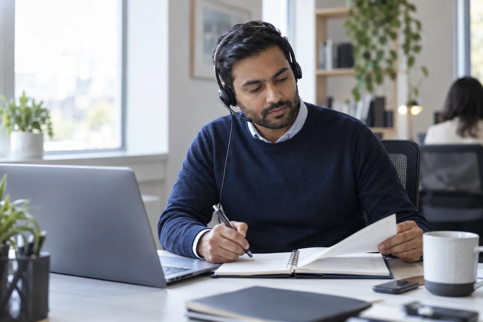 An appointment coordinator checking a paper planner beside a laptop